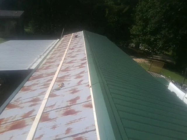 Old rusted panels beside newly installed green metal roofing — Wind Damage Roof Repair by Roofing Brothers in Fall River