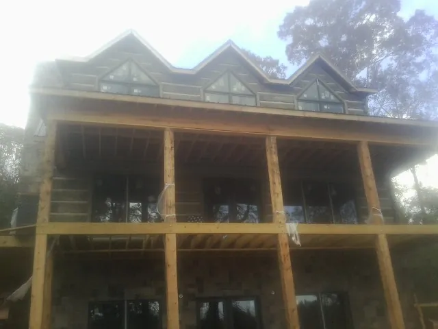 Dormers and porch framing on a large log home under construction — Roof Coating work by our crew in Fall River