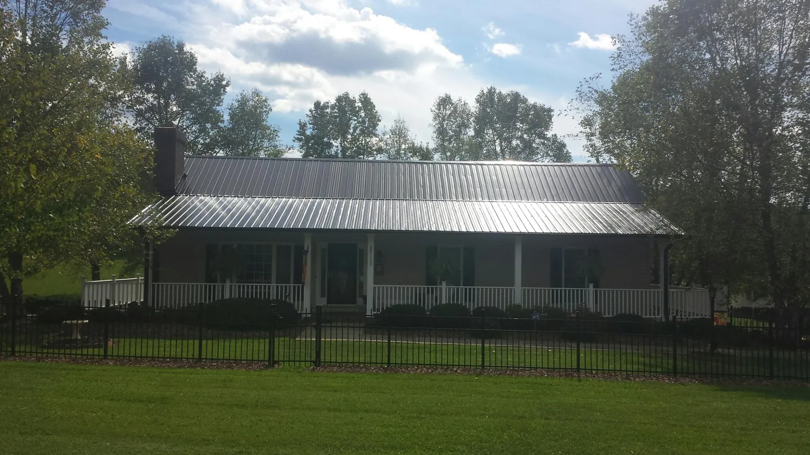 Gray metal roof on a brick ranch with a full width front porch — Gutter Guard Installation work by our crew in Fall River