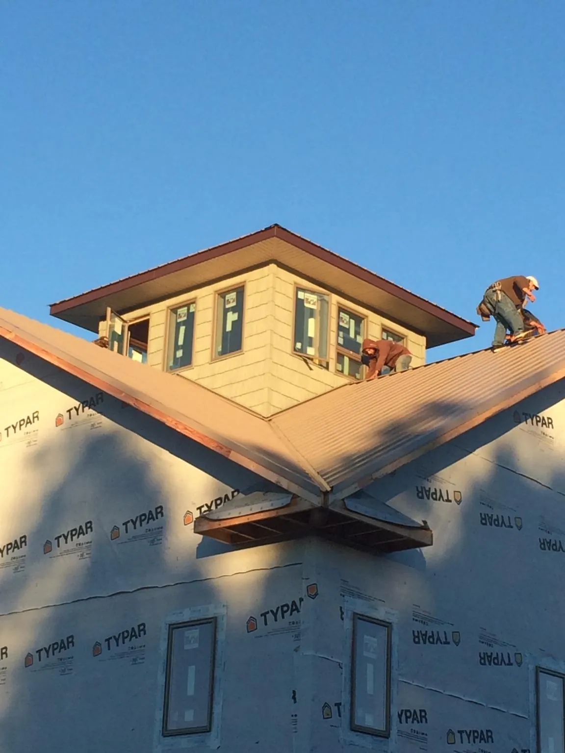 Roofers working around a rooftop cupola on a new metal roof at sunset — Roof Waterproofing in Fall River by Roofing Brothers